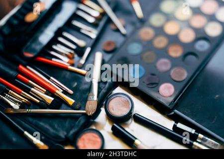 Makeup artist set. A palette of eyeshadows in different colors and a set of makeup brushes with blush in a black cosmetic bag. Stock Photo