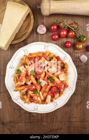 Overhead photo of penne pasta with chicken, tomato sauce and ingredients with copy space Stock Photo