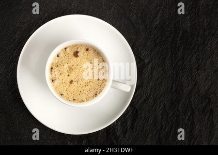 A cup of regular coffee with foam on a dark black background Stock Photo