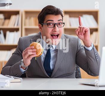 Hungry funny businessman eating junk food sandwich Stock Photo