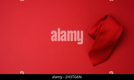 Twisted silk red tie on a red background Stock Photo