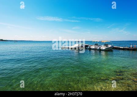 Group of small speedboats moored on the coast of Lake Garda in front of the Bardolino village, tourist resort in Verona, Veneto, Italy, Europe. Stock Photo