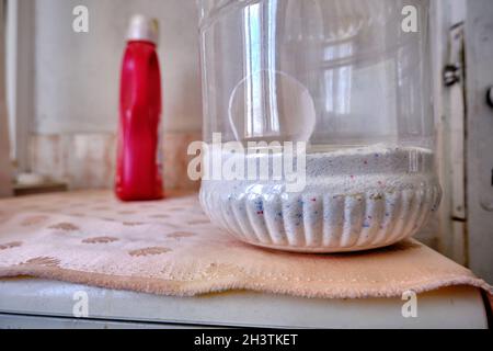 Detergent and washing agent for colorful clothes with red color softener box on washing machine. Stock Photo