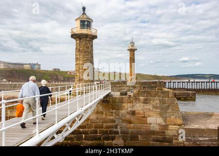 elderly couple walking  on pier East & west  lighthouse on Whitby harbour Stock Photo