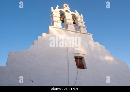 Greece, Cyclades. Folegandros island, Old church belfry at Chora town. Traditional Cycladic chapel, whitewashed walls, clear blue sky background. Stock Photo