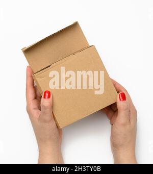 Two female hands hold a square box made of brown corrugated cardboard on a white background Stock Photo