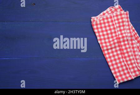 Folded red and white cotton kitchen napkin on a wooden blue background, top view Stock Photo