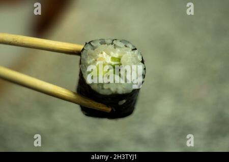 Sushi holds with sticks. Sushi with rice and cucumber. Asian cuisine. Fresh food. Stock Photo