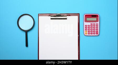 Pink calculator, folder with blank white sheets and black magnifier on a blue background. Banner for business Stock Photo