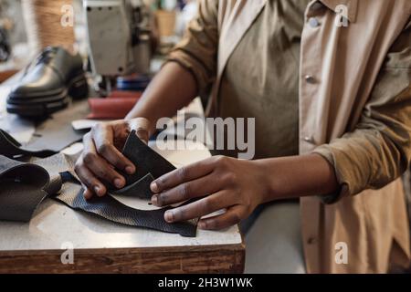 Close-up of tailor sitting at the table and examining the pieces of leather during her work in the workshop Stock Photo