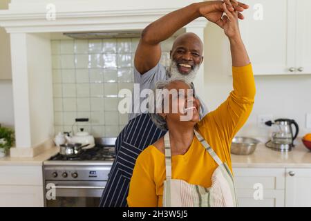 Senior african american couple dancing together in kitchen smiling Stock Photo