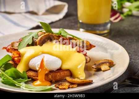 Eggs Benedict with bacon, mushrooms and hollandaise sauce on plate Stock Photo