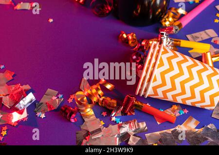Party tinsel and colorful cups close up on purple background Stock Photo
