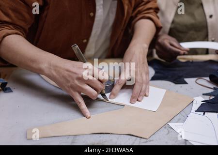 Close-up of dressmaker using pattern to cut the fabric at the table, she sewing the clothes Stock Photo