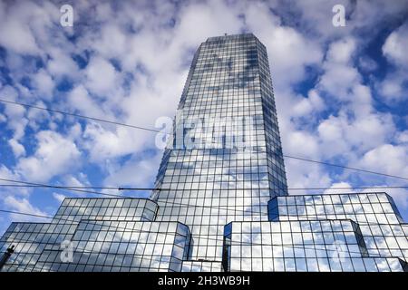 A modern reflective office skyscraper against a blue sky with white clouds. Warsaw, Poland Stock Photo