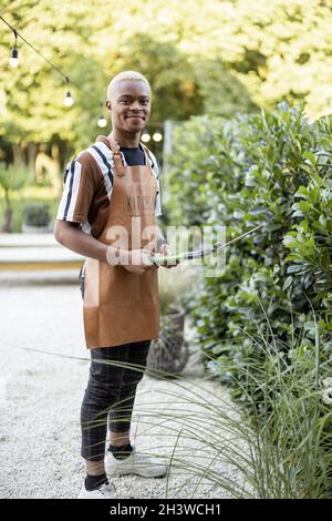 Man cuts plant with gardening scissors in garden Stock Photo