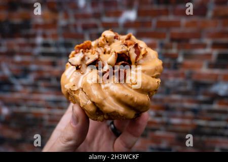 a close up of a person holding a bacon maple donut. Stock Photo