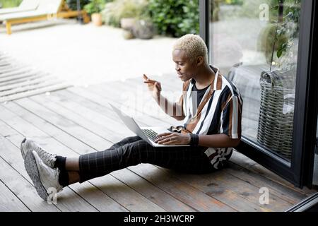 Black man using laptop computer on terrace at home Stock Photo
