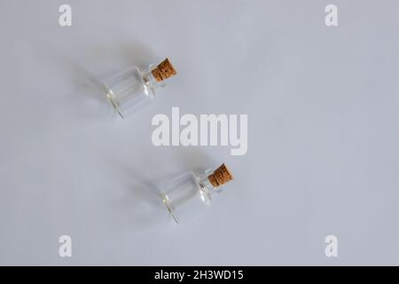 Two empty small glass bottles with cork stoppers on gray background. Side lighting. Horizontal photo. Copy space. Close-up. Selective focus. Stock Photo