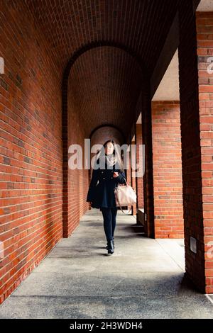 A young women walking down a brick archway. Stock Photo