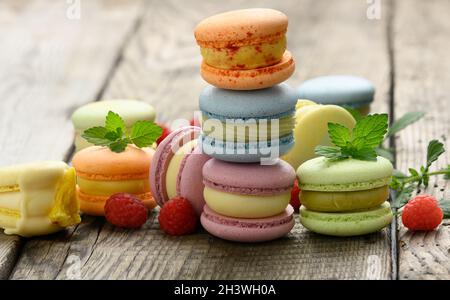 Stack of baked multicolored macarons and different flavors on a gray wooden table, delicious dessert Stock Photo