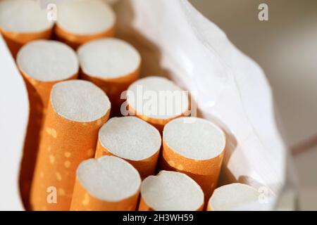 A pack of cigarettes is open and there are several cigarettes in an already incomplete pack. These are filter cigarettes. Stock Photo