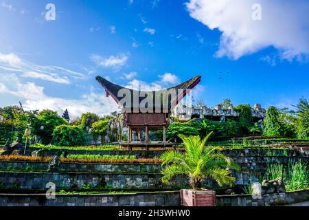 Stunning views of hanging gardens with numerous plants, flowers and palm trees, old buildings, statues and birds in the cloudy sky Stock Photo