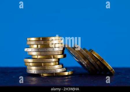 Euro coins shown on blue background. The surface on which these coins are placed is dark blue. Stock Photo