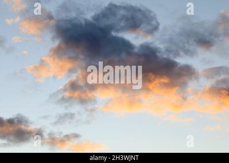 The clouds in the sky are lit up by the rays of the setting sun. Stock Photo