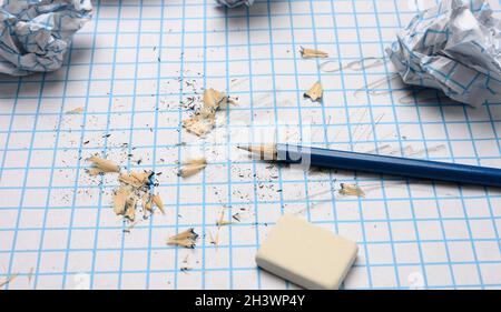 Crumpled paper balls and a sharpened wooden pencil with shavings on a checkered paper sheet Stock Photo