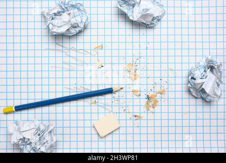Crumpled paper balls and a sharpened wooden pencil with shavings on a checkered paper sheet Stock Photo