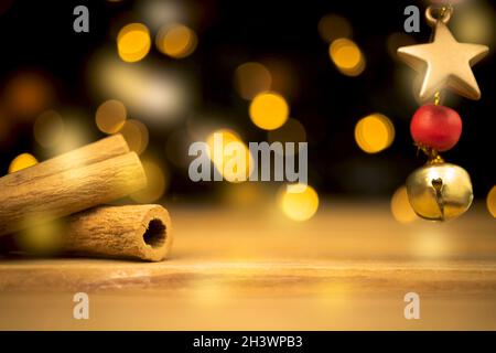Empty wooden table with blurred christmas lights at background. Wooden table with new year decoration, cinnamons and golden star closeup Stock Photo