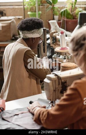 Dressmakers sewing clothes on sewing machines during their work in the factory Stock Photo