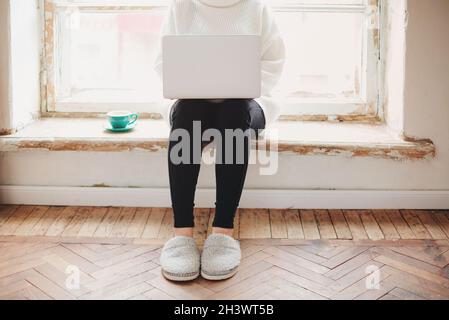 Crop woman using laptop near window in morning Stock Photo