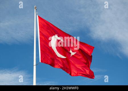 Giant Turkish Flag waving in the sky. Red, the blood of martyrs; the white moon represents Islam and the white star represents Turkishness. Stock Photo