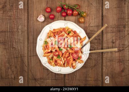 Penne pasta with tomato sauce, fork and spoon plunged into plate Stock Photo