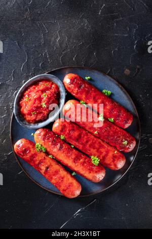 Grilled sausages with ketchup, shot from above on a dark background Stock Photo