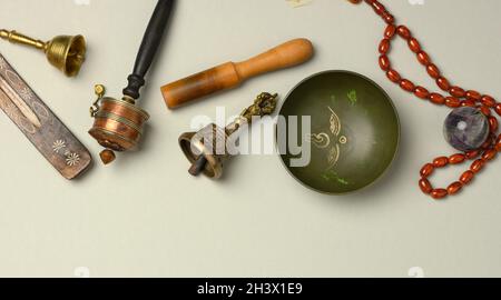 Tibetan singing copper bowl with a wooden clapper on a gray background, objects for meditation and alternative medicine Stock Photo