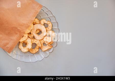 Paper bag with dried sliced apple chips - healthy trendy snacks on the plate. Top view. Proper nutrition concept. High quality photo Stock Photo