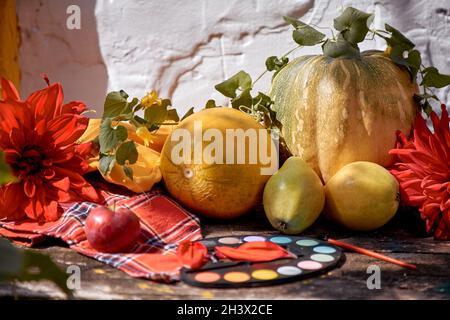 Autumn aesthetic fair: yellow fruits and vegetables and bright paints with a brush, pumpkin, pears, apple and melon. Thanksgiving Day concept. Autumn still life with red georgine, modern shadows. High Stock Photo