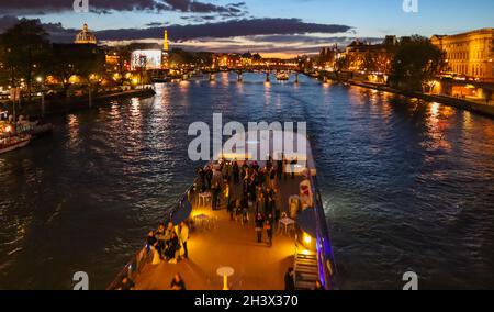 Beautiful night Paris, sparkling Eiffel tower, bridge Pont des Arts over the River Seine and touristic boats. France Stock Photo