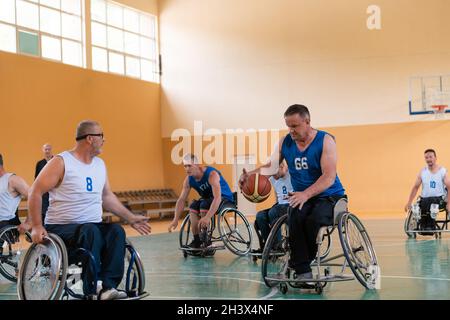 Disabled War veterans mixed race opposing basketball teams in wheelchairs photographed in action while playing an important matc Stock Photo