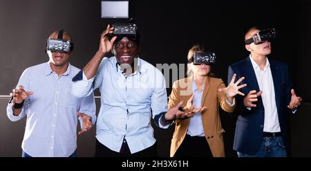 Cheerful nice friends playing video games using virtual reality glasses Stock Photo