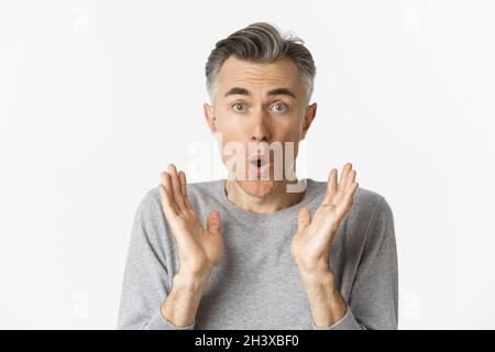 Close-up of surprised, handsome middle-aged man, saying wow and looking at cool promo offer, standing over white background Stock Photo