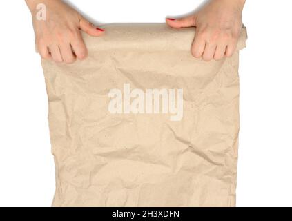 Female hands holding a rolled roll of brown crumpled paper isolated on white background Stock Photo
