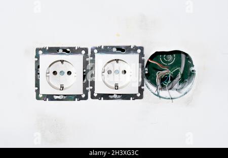 socket faceplate without frame. two ready-made sockets and one hole for unrepaired socket on the wall with wires. unrepaired socket back boxes with Stock Photo