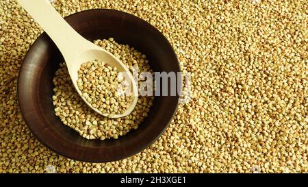 Raw green buckwheat in a brown clay plate and a wooden spoon. Vegan organic food concept. The concept of diet, weight loss, heal Stock Photo