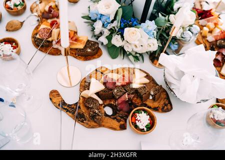 Cutting boards with cheese, prosciutto, and black bread on the festive table. Stock Photo