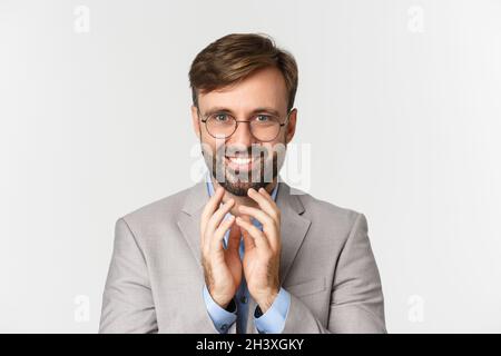 Close-up of bearded businessman in glasses and suit, scheming something, smiling devious and having perfect plan, standing over Stock Photo