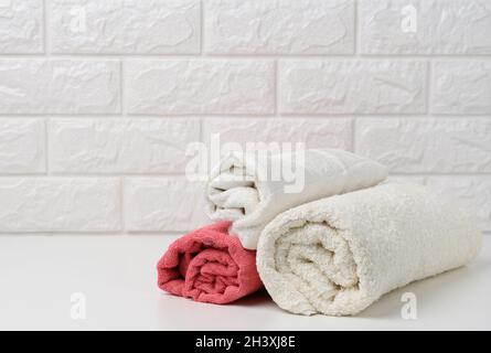 Clean white rolled terry towels on white shelf, bath interior Stock Photo